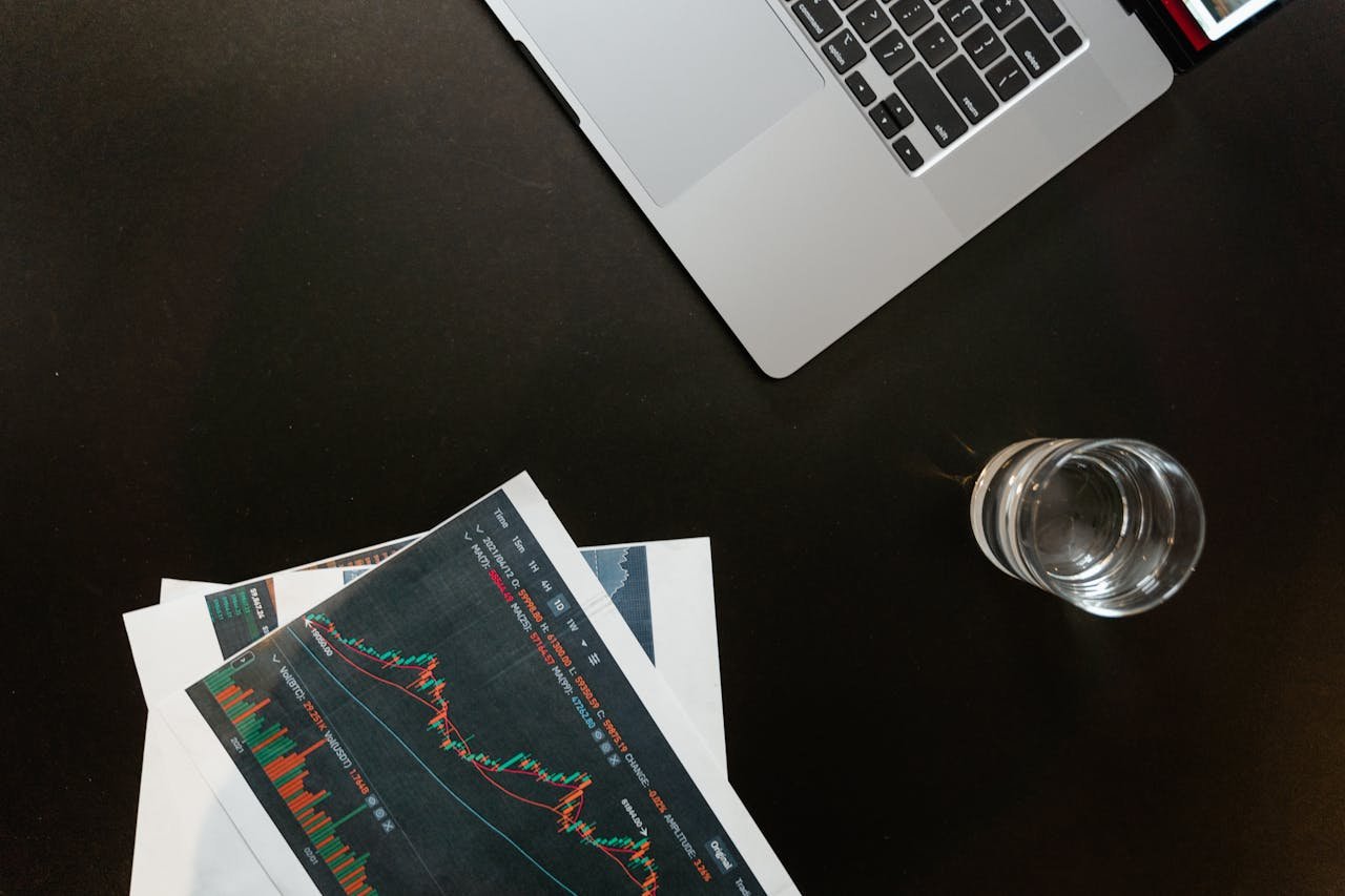 services-02 Professional workspace featuring financial graphs, laptop, and glass of water on a sleek desk.